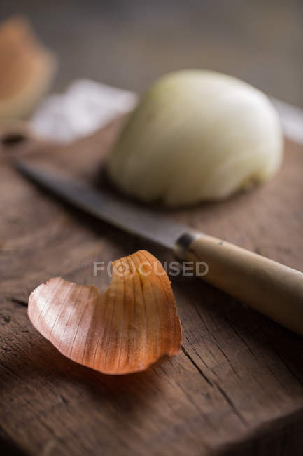 Primer plano de la piel de cebolla sobre tabla de cortar de madera - foto de stock