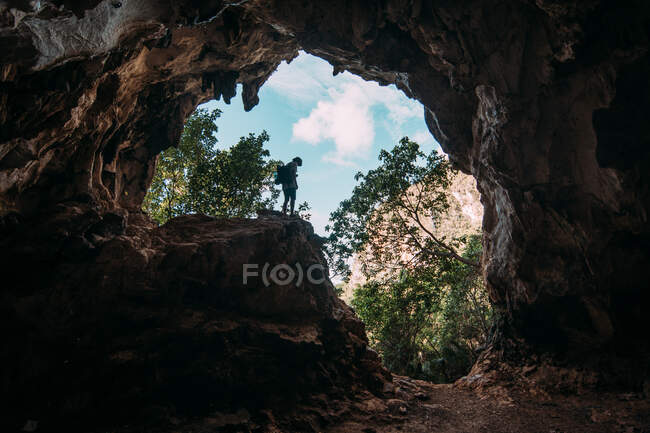 Vista de dentro de caverna rochosa de pessoa de pé sobre pedra no fundo de madeiras verdes de Cuba. — Fotografia de Stock