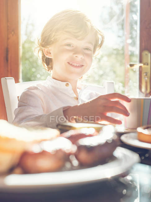 Bambino con coppa seduto a tavola — Foto stock