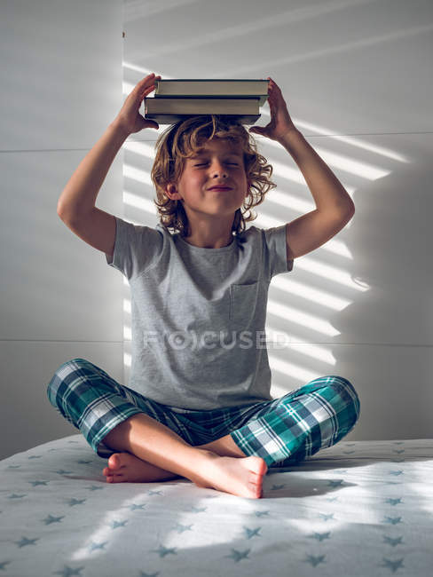 Мальчик с книгами над головой — стоковое фото