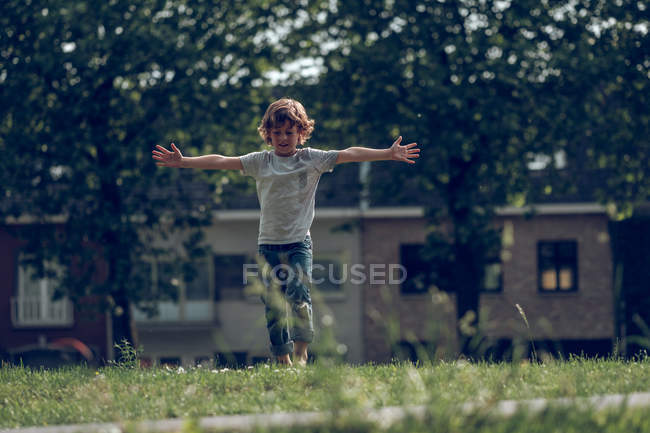 Возбужденный мальчик прыгает по траве — стоковое фото
