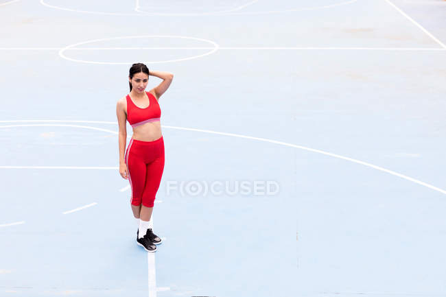 Jeune femme souriante debout sur un terrain de sport — Photo de stock