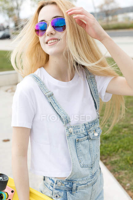 Блондинка с пенни-доской гуляет по парку — стоковое фото
