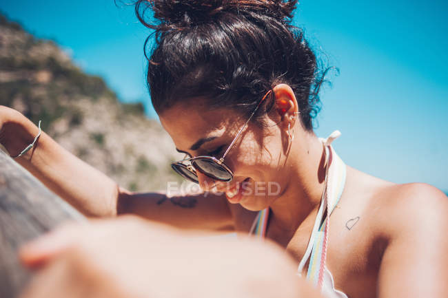 Close-up of smiling young girl in sunglasses on rocky coast — Stock Photo