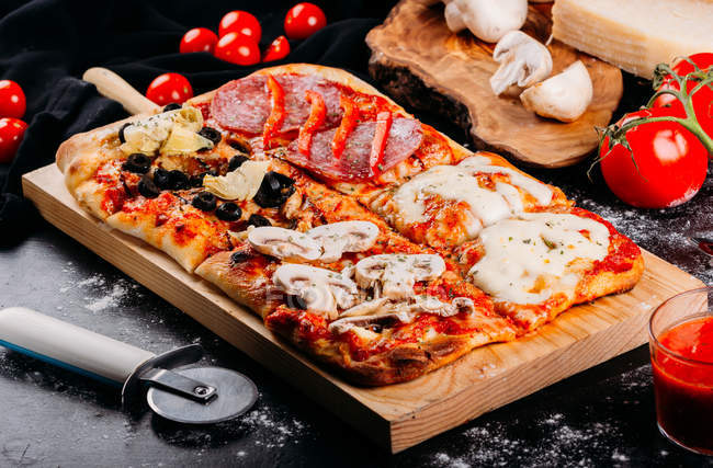 Pizza coupée au fromage, sauce et aubergines tranchées sur planche de bois sur table noire — Photo de stock