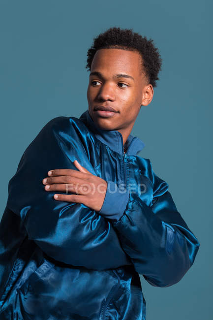 Портрет молодого чорного чоловіка в блакитному вбранні з перехрещеними руками, дивлячись подалі — стокове фото