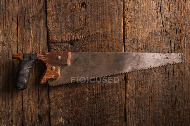 Carpenter rusty handsaw on wooden surface — Stock Photo