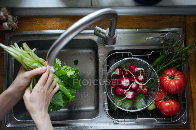 Hands washing fresh vegetables in kitchen sink — Stock Photo