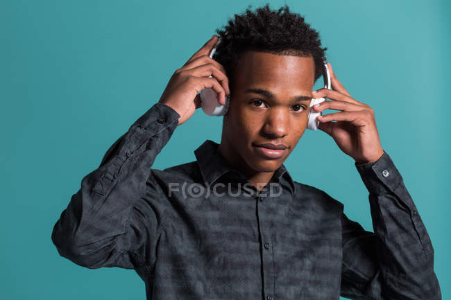 Portrait of Casual black man holding headphones on blue background — Stock Photo