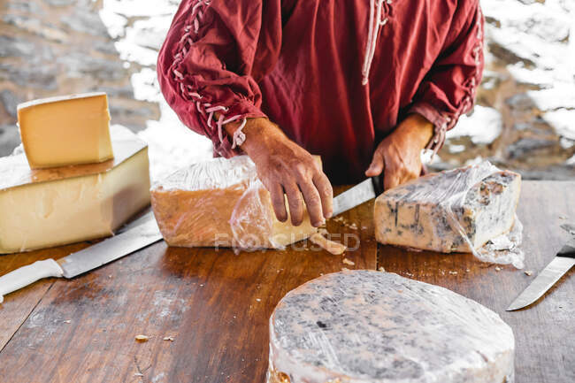 Couper la main du vendeur en donnant au client un morceau de fromage sur le couteau pour la dégustation — Photo de stock