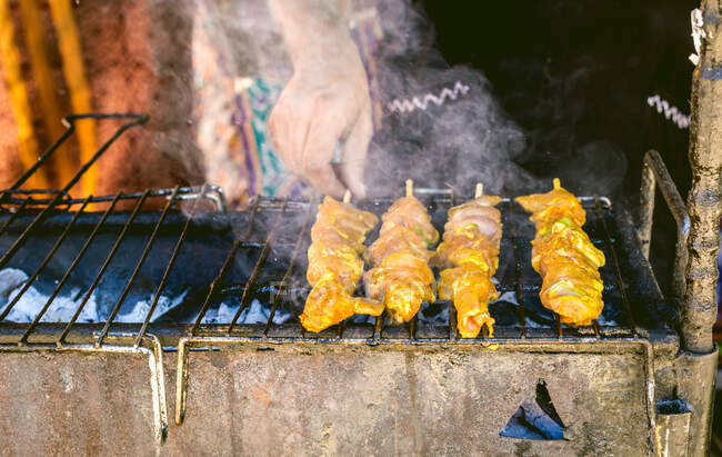 Cultivo irreconocible persona convirtiendo carne ensartada mientras se cocina en la parrilla - foto de stock