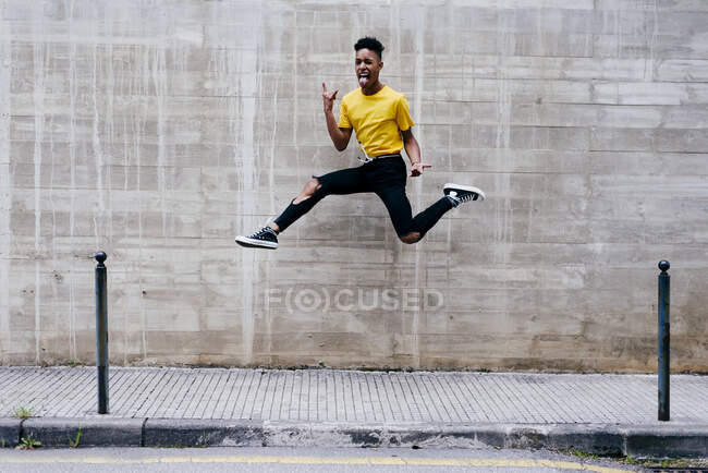 Excited ethnic teenager jumping on street — Stock Photo