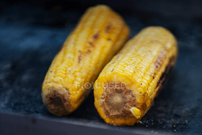 Gros plan de délicieuses épis de maïs jaunes cuites sur le gril et disposées sur le stalle — Photo de stock