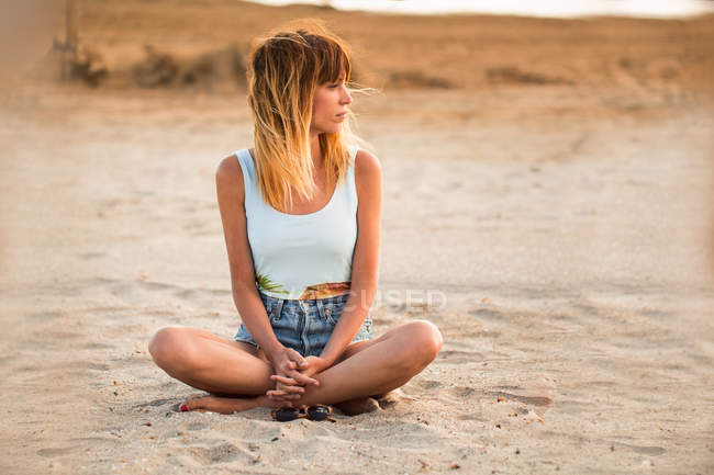 Chilling woman sitting on beach with legs crossed — Stock Photo