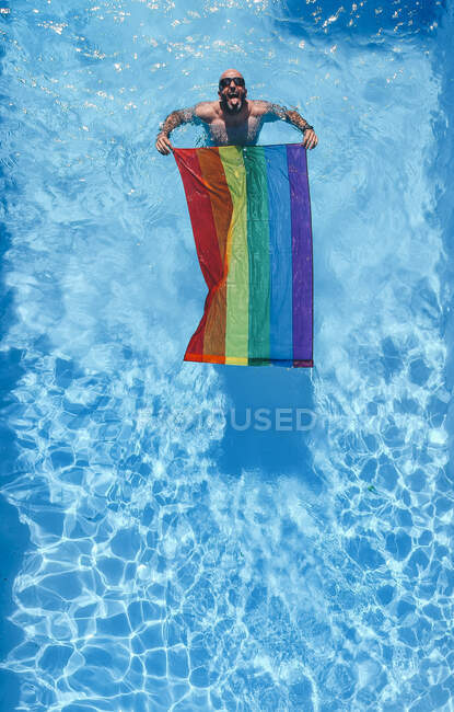 Gay l'homme avec gay fierté drapeau dans piscine. — Photo de stock