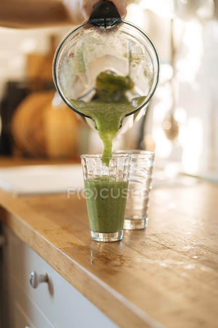 Human hand pouring smoothie in glass — Stock Photo