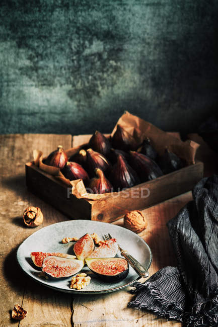 Свежие инжиры подаются на тарелке с орехами на деревенском столе — стоковое фото