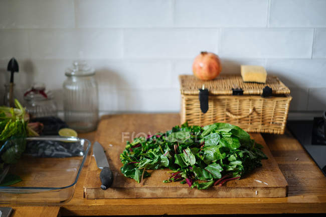 Folhas de espinafre verde em tábua de corte de madeira na cozinha — Fotografia de Stock