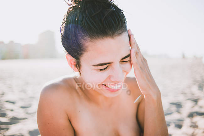 Primer plano de la chica riendo en la playa con los ojos cerrados - foto de stock