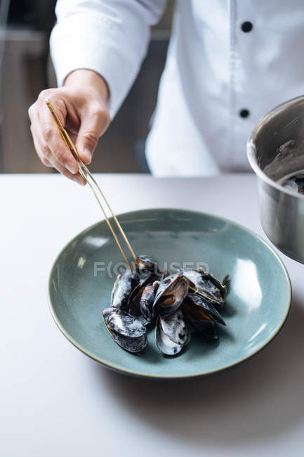 Gros plan du chef servant un plat nordique de fruits de mer avec des moules sur l'assiette — Photo de stock