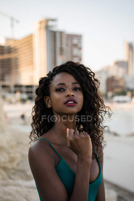 Portrait of young woman with curls posing and looking in camera outdoors — Stock Photo