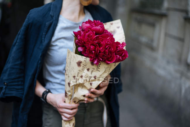 Крупным планом женщины, держащей букет розовых пионов в оберточной бумаге — стоковое фото