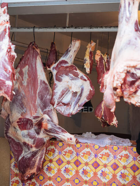 Part of huge raw beef hangs on hook in shadow of room — Stock Photo