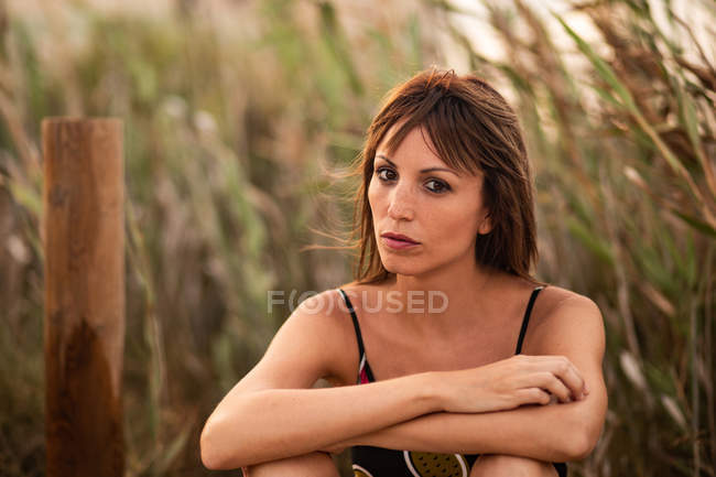 Жінка в літньому вбранні сидить у польовій траві — стокове фото