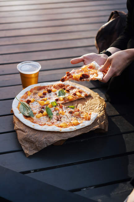 Крупным планом женских рук с кусочком пиццы — стоковое фото