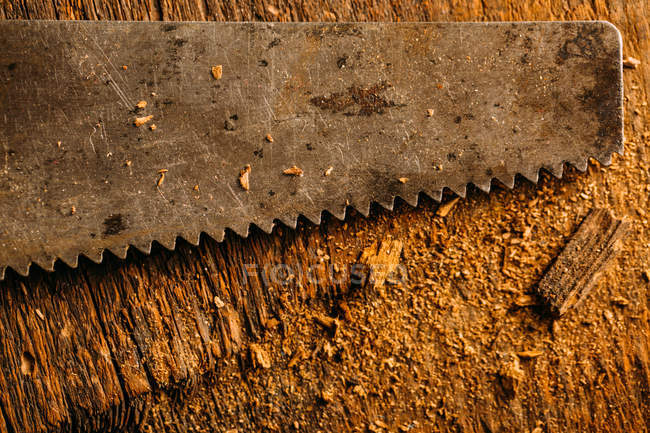 Gros plan de la scie à main rouillée sur la surface en bois — Photo de stock