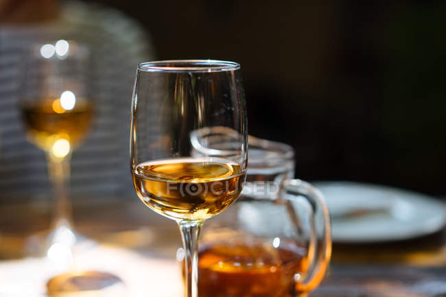 Close-up of glass of white wine and pitcher on wooden table — Stock Photo
