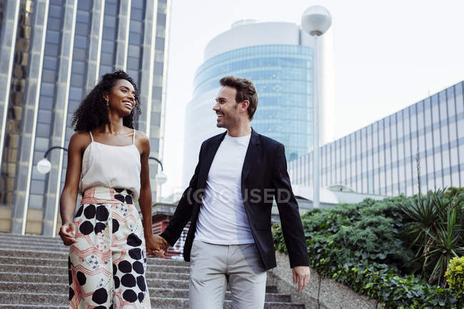 Smiling elegant couple walking down stairs together on city street — Stock Photo