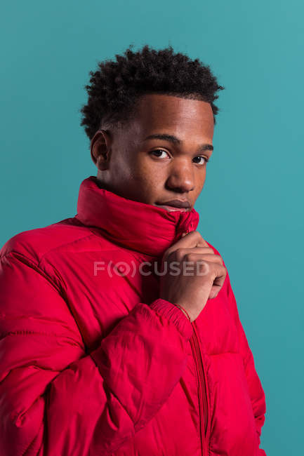 Портрет модного чоловіка в червоній пухнастій куртці на синьому фоні — стокове фото