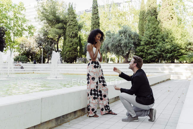 Улыбающийся мужчина делает предложение женщине в парке — стоковое фото