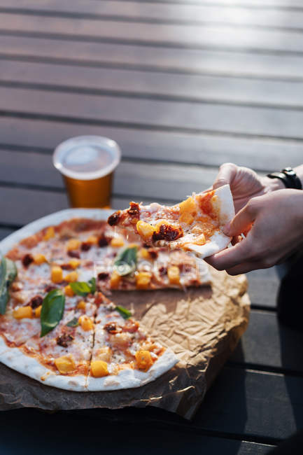 Крупним планом жіночі руки беруть шматочок піци — стокове фото
