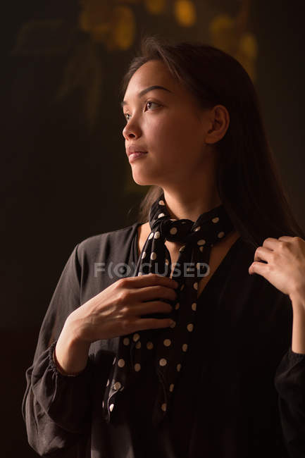 Confident woman tying neckerchief and looking away — Stock Photo