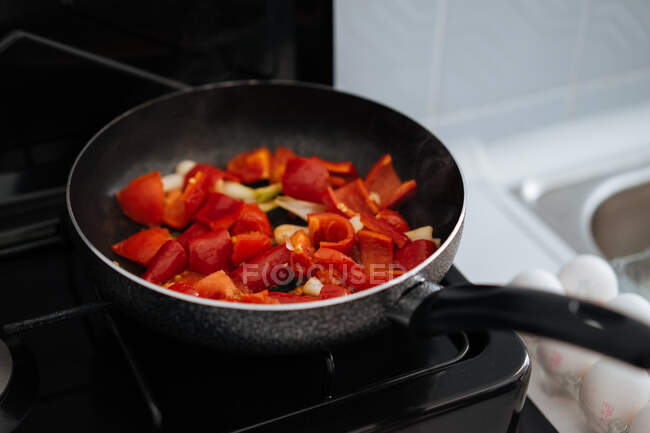 Crop female hand stirring with wooden spatula chopped vegetable leaves being cooked in pot on gas stove — Stock Photo