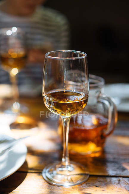 Gros plan du verre de vin blanc et du pichet sur une table en bois — Photo de stock
