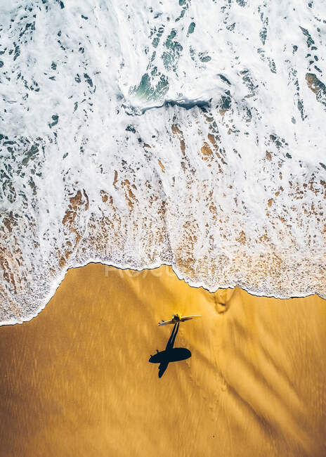 Surfista caminando con tabla en la playa - foto de stock