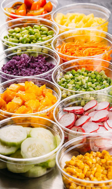 Set of plastic bowls of assorted vegetarian ingredients for food preparation — Stock Photo