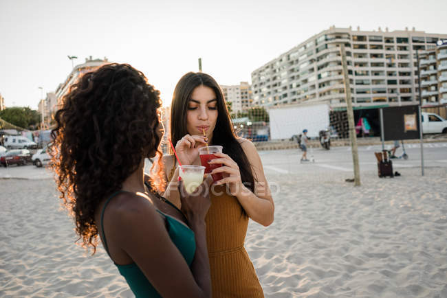 Молодые женщины наслаждаются напитками в мягком свете на побережье города — стоковое фото
