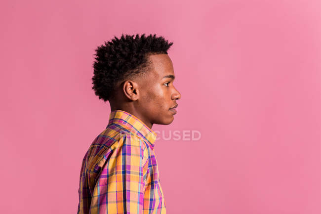Hipster hombre negro en camisa de colores de pie sobre fondo rosa - foto de stock