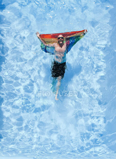 Gay hombre con gay orgullo bandera en piscina. - foto de stock