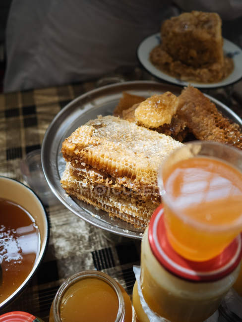 Primo piano di nido d'ape su piatto e vasi di miele fresco su tavolo rustico — Foto stock