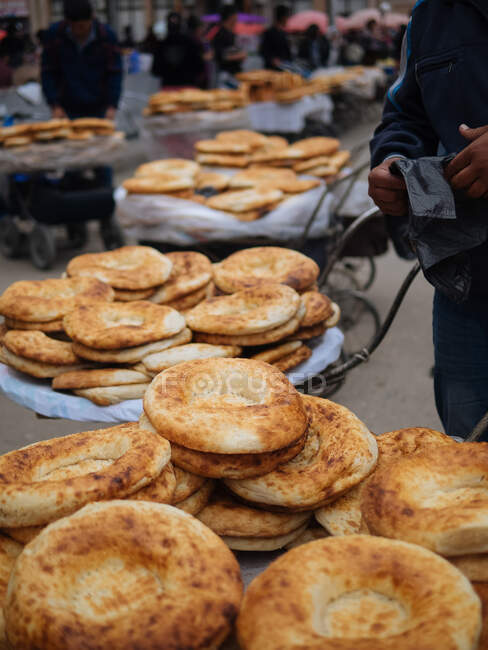 Pessoa de cultura sem rosto em pé perto de pilha de pão de naan caseiro no mercado — Fotografia de Stock