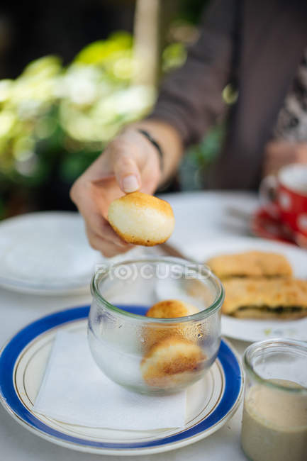 Close-up of female hand taking pastry from jar on garden table — Stock Photo
