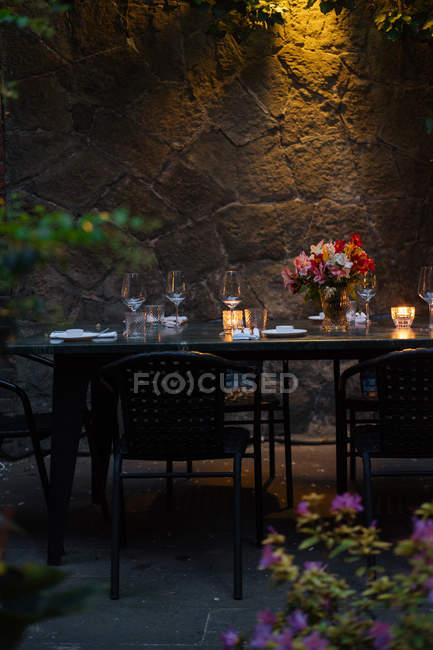 Setting table decorated with candles and flowers at night on backyard — Stock Photo