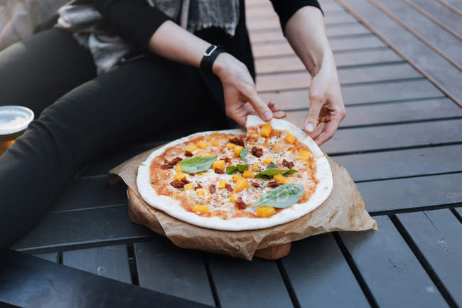 Женщина сидит на улице со стаканом пива и печет вкусную пиццу — стоковое фото