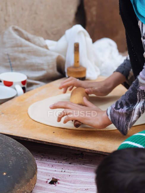 Manos femeninas laminando hoja de masa en tablero de madera - foto de stock