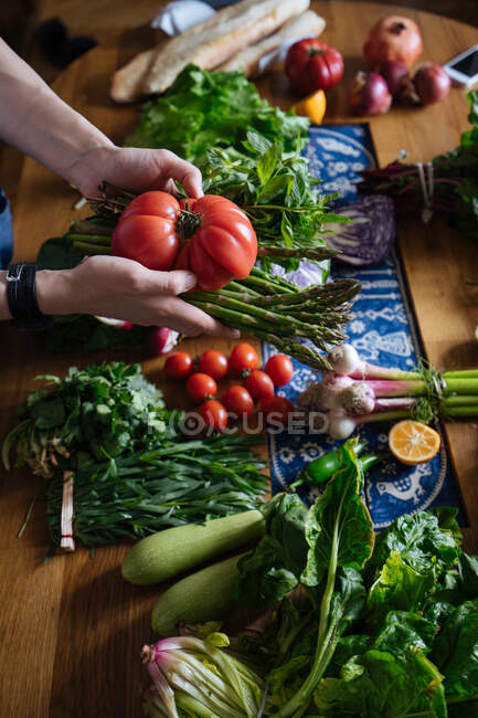 Vista de la cosecha de manos femeninas tomando potherbs de mesa elegante con verduras frescas y saludables ingredientes de cocina de frutas desde arriba - foto de stock